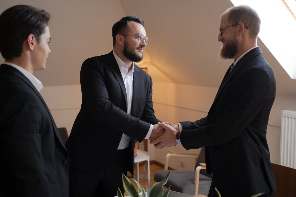 Bearded Men in Black Suit Doing Handshake while Looking at Each Other