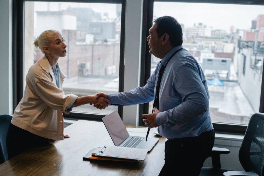 Young woman shaking hands with boss after business presentation