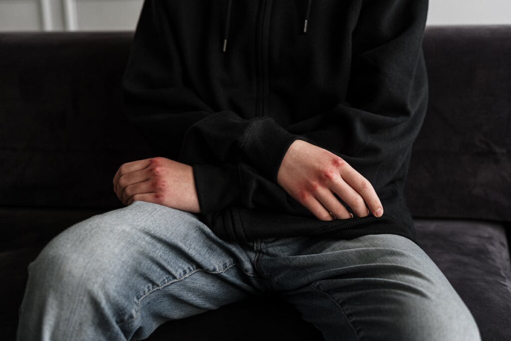 Person in Black Jacket and Blue Denim Jeans Sitting on Black Couch